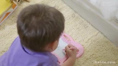 快乐的亚洲klid小男孩在家里的磁板上写在地毯上。有趣的孩子玩磁力画板。教育学习绘画概念。背景色